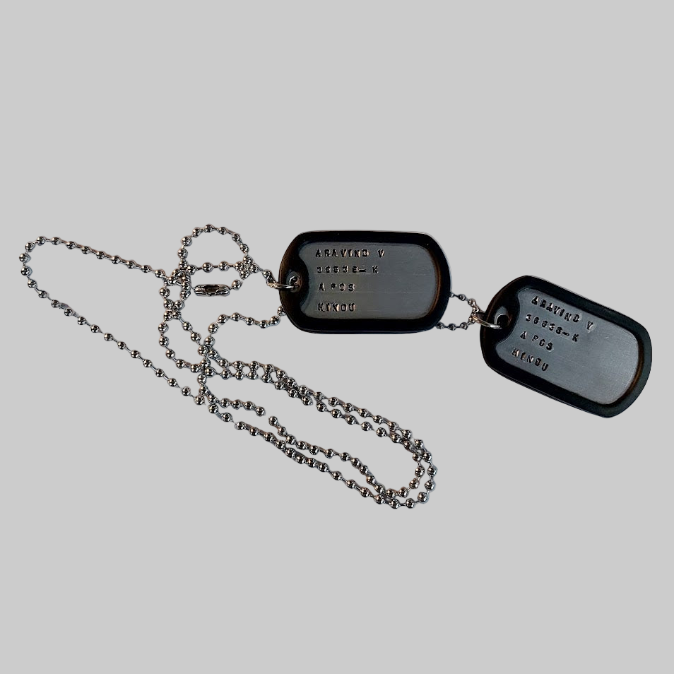 Dog tags with chain on a piece of paper, likely used for documentation or display.