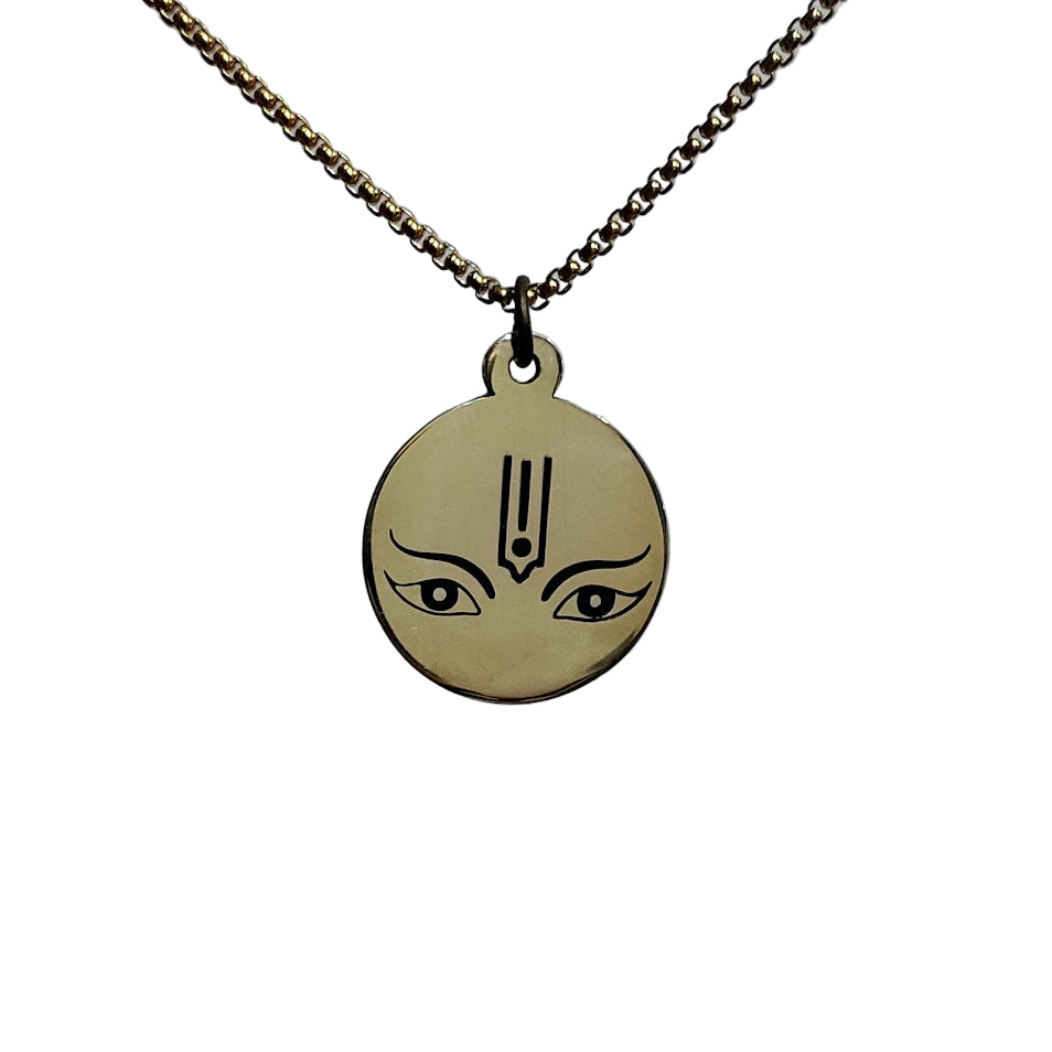 Gold pendant with face design on a chain against a light gray background