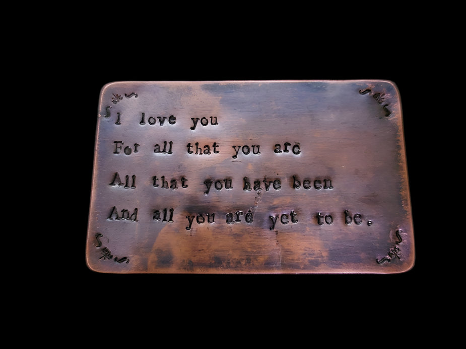 Copper plaque with engraved text on a black background