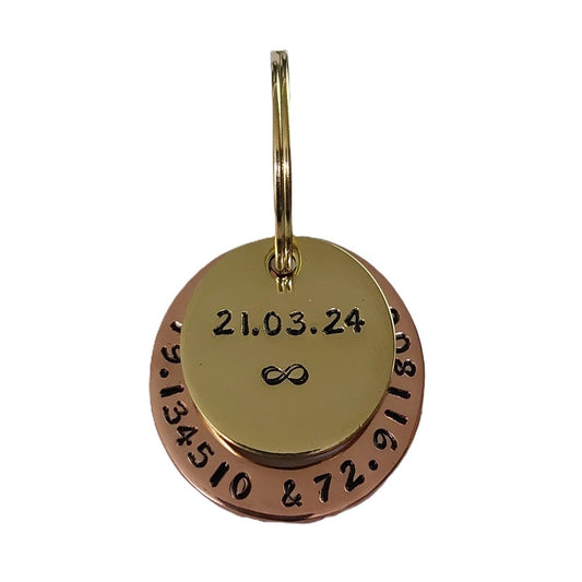 Close-up of hand-stamped brass and copper keychain personalized with a custom date and infinity symbol