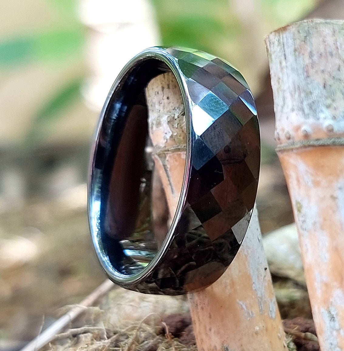 Classic Wide black ceramic ring resting against bamboo stalks, outdoor lifestyle shot