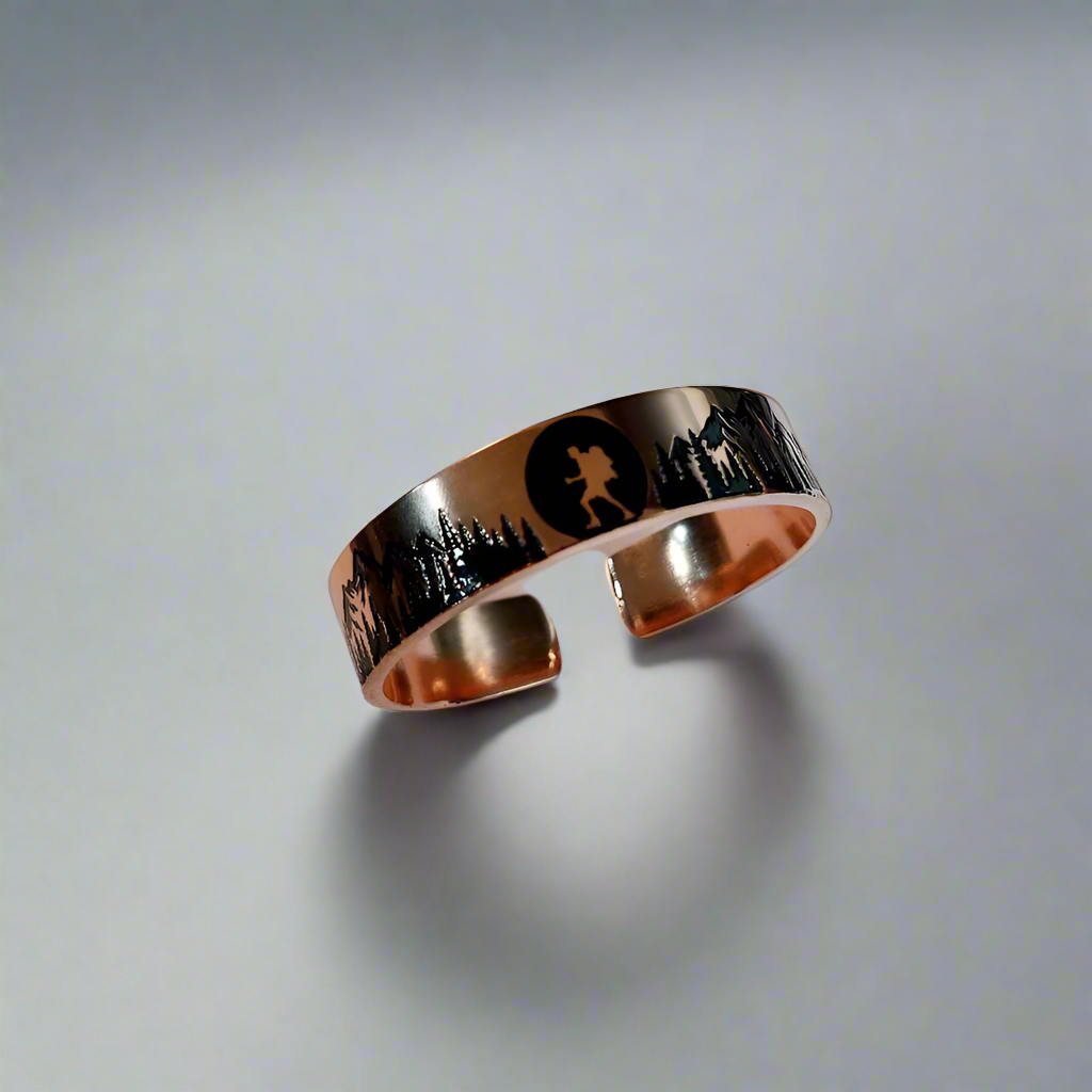 Rose gold ring with engraved design on a piece of paper with writing.
