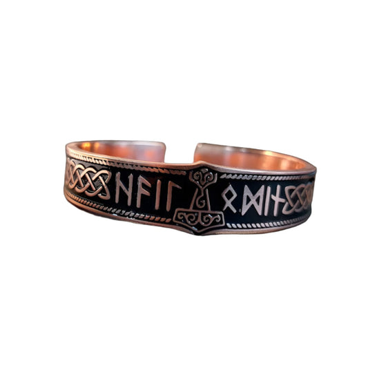 Copper bracelet with engraved designs on a black background