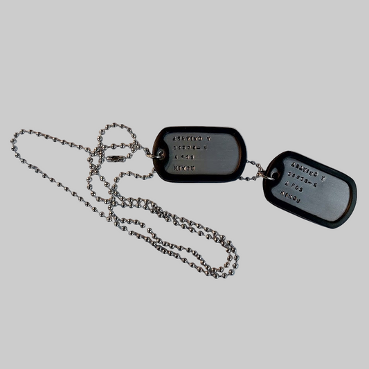 Dog tags with chain on a piece of paper, likely used for documentation or display.