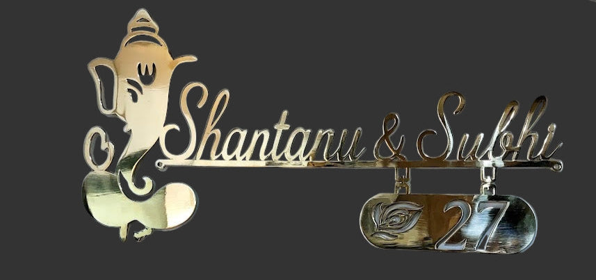 Decorative nameplate with 'Shantanu & Swati' and a Ganesha figure on a dark background.