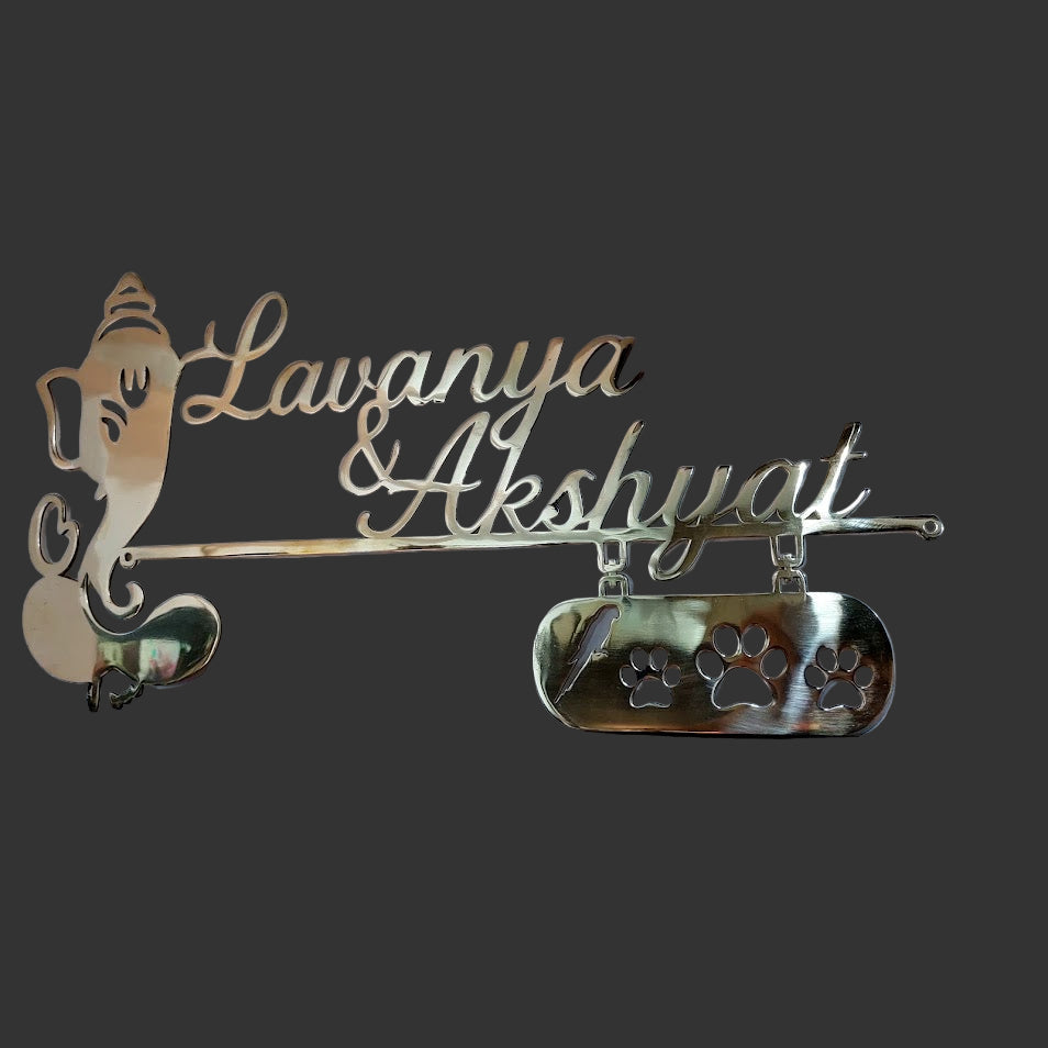 Decorative nameplate with 'Lavanya & Akshyvat' and a Ganesha figure on a dark background