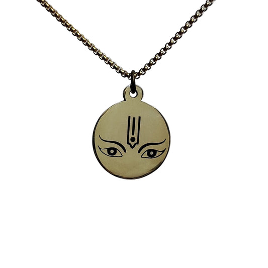 Gold pendant with face design on a chain against a light gray background