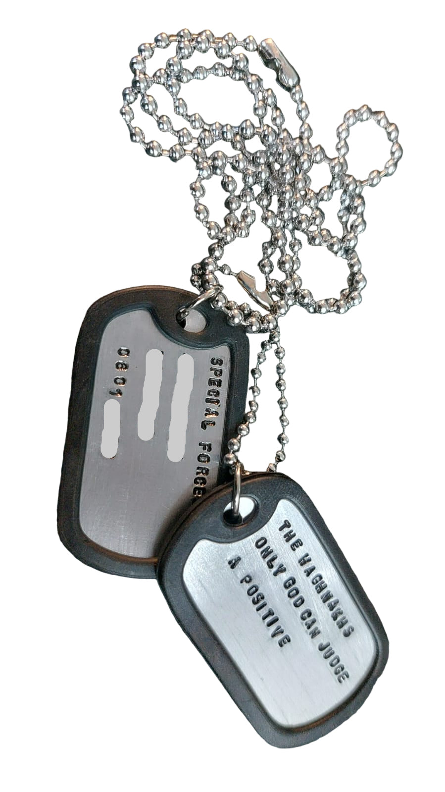 Two silver dog tags on a chain against a dark background