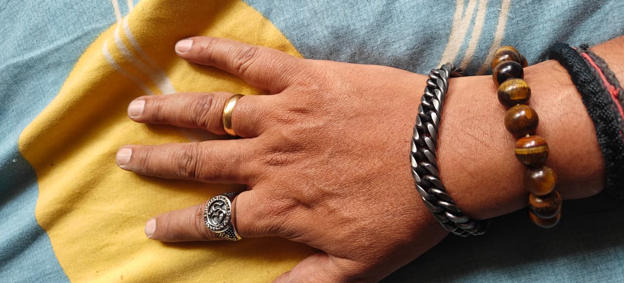 Hand with rings and bracelets on a yellow and blue fabric background
