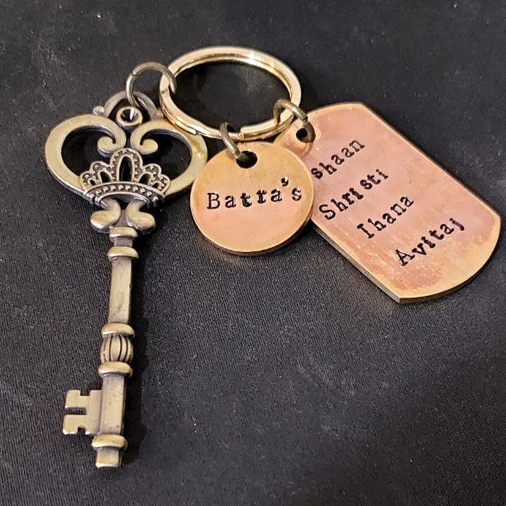 Key-shaped keychain with three copper tags on a dark background